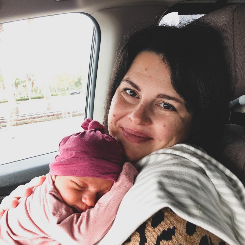 a woman holding a sleeping newborn baby in a car